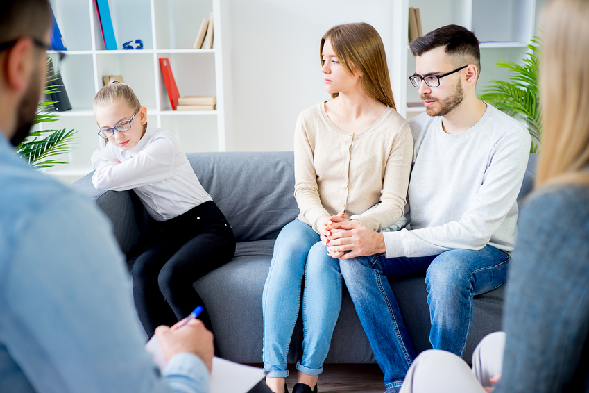 Family of three talking with psychologist. Psychologist taking notes.